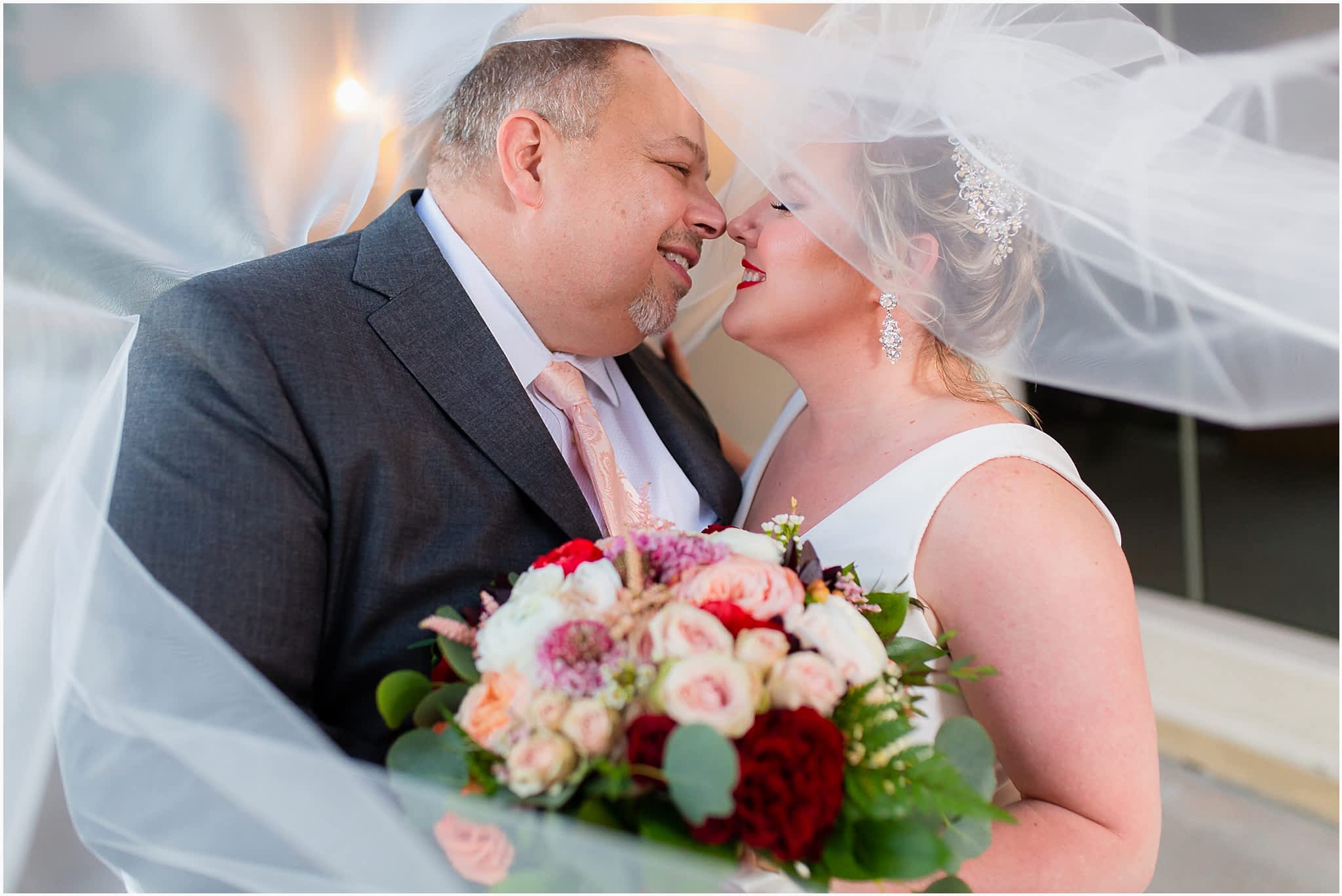 intimate and unique veil shot of bride and groom leaning into each other to kiss