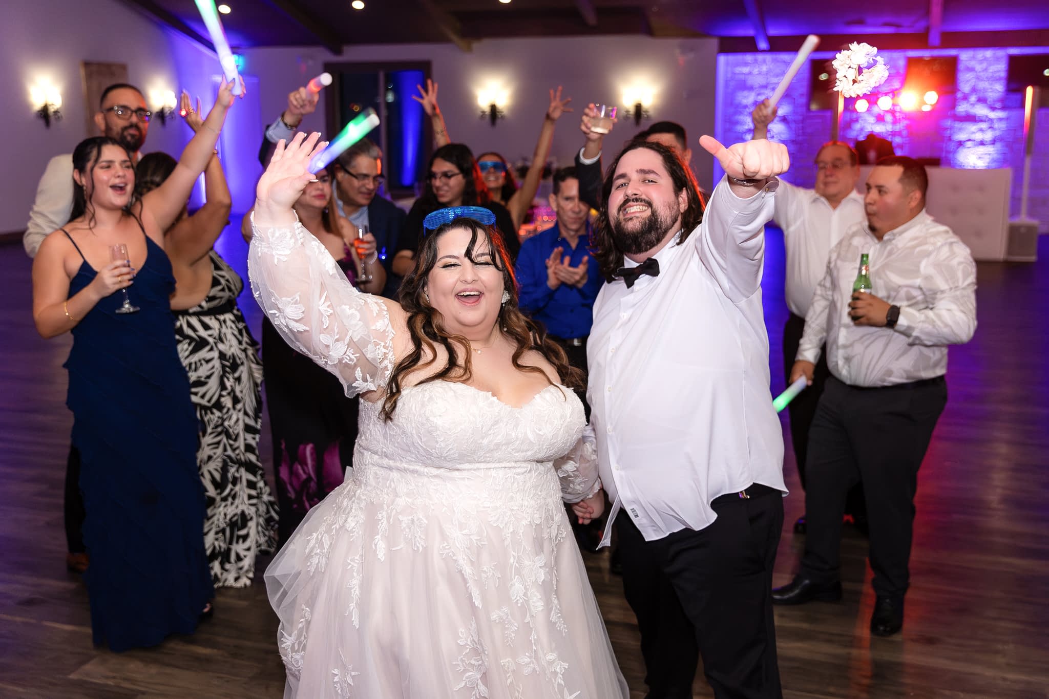 Bride and groom living it up on the dance floor with friends during wedding reception at Hidden Pines Chapel in Highland Village